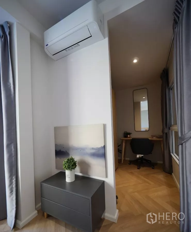 Townhouse for rent or sale in Watthana, Bangkok - Bedroom corner with air-conditioning unit and doorway to compact study.