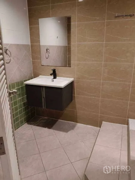 Retail Space for rent in Khlong Toei, Bangkok - Bathroom vanity with mirror and sink cabinet against beige wall tiles.