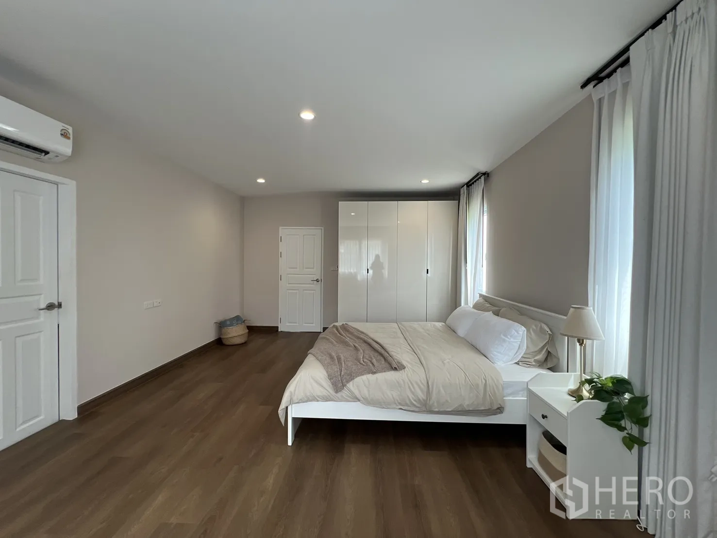 Detached House for rent in Mueang Samut Prakan, Samut Prakan - Large bedroom with windows on two sides and wood flooring.
