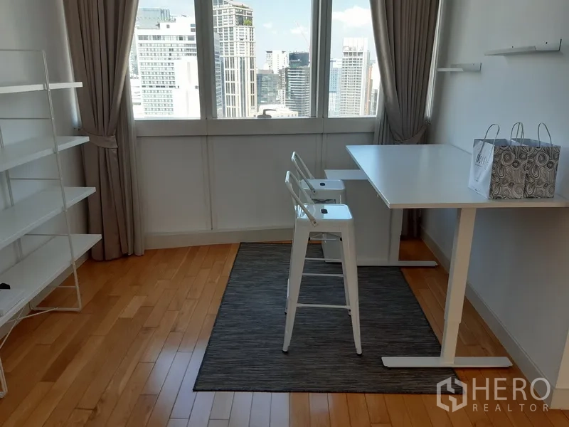 Condominium for rent in Khlong Toei, Bangkok - Bright study or multipurpose room with city views and shelving.
