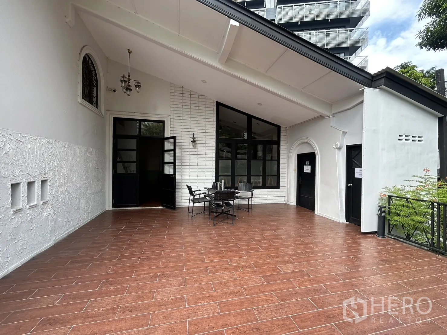 Retail Space for rent in Bangkok - Large covered terrace with wood-look tiles, black-framed glass doors and outdoor seating.