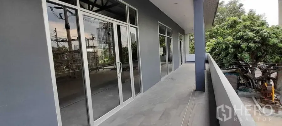 零售空间 出租在Khlong Toei, Bangkok - 带顶宽阳台，多个玻璃店面与铝合金门窗，眺望绿树景观。