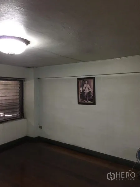 Shophouse for rent in Phra Khanong, Bangkok - Simple bedroom with wood floor, window, and ceiling light fixture.