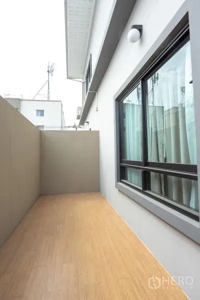 Home Office for rent in Bang Khen, Bangkok - Private side terrace with wood-look flooring and large sliding window along the exterior wall.