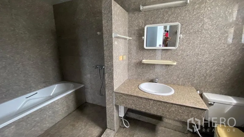Townhouse for rent in Bang Na, Bangkok - Bathroom featuring a bathtub, stone-look tiles and long countertop vanity.
