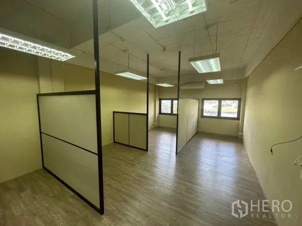 Office Space for rent in Chatuchak, Bangkok - Private workstations with tall partition panels, hanging LED lights and windows inside a compact office room.