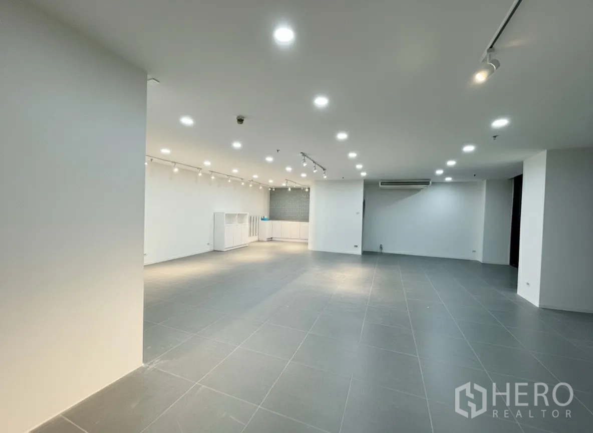 Retail Space for rent - Spacious open-plan interior with grey tile flooring, white walls, and recessed plus track lighting.