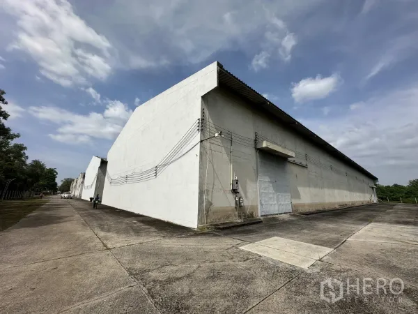 Warehouse for rent in Phra Nakhon Si Ayutthaya - Long row of concrete warehouses with wide driveway and loading doors.