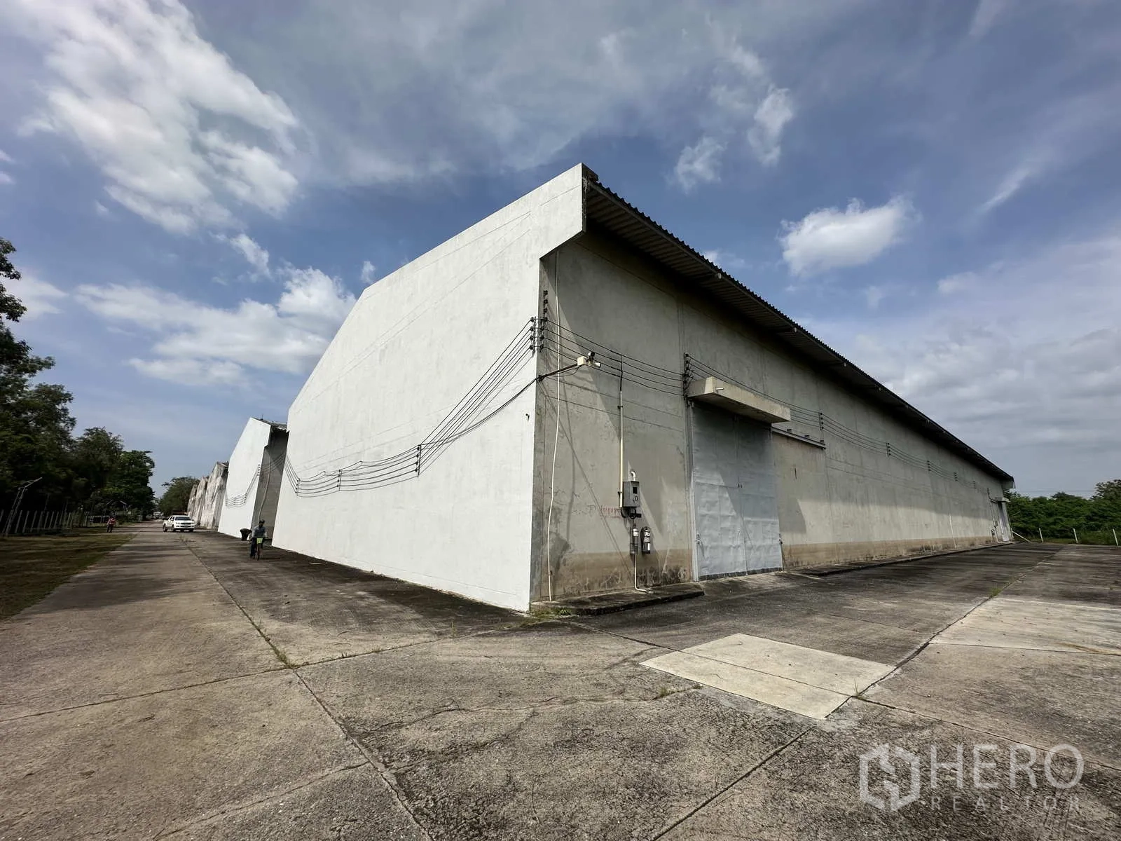 Warehouse for rent in Phra Nakhon Si Ayutthaya - Long row of concrete warehouses with wide driveway and loading doors.