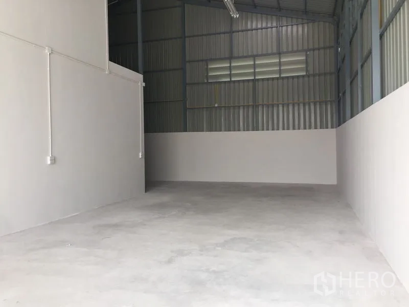 Warehouse for sale in Khlong Luang, Pathum Thani - Empty high-ceiling warehouse interior with concrete floor and metal cladding.