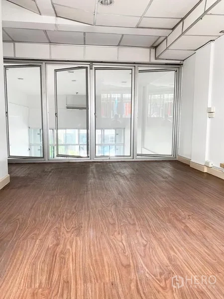 Townhouse for rent in Khlong Toei, Bangkok - Bright room with wood-look flooring and full-height glass partition doors in a Khlong Toei townhouse.
