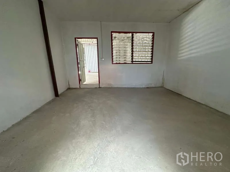 Warehouse for rent in Suan Luang, Bangkok - Empty office room with louvered window and bare concrete flooring inside the warehouse.