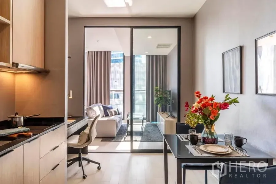 Condominium for rent in Pathum Wan, Bangkok - View from kitchen to living room through sliding doors, featuring a two-seat dining table with flowers.