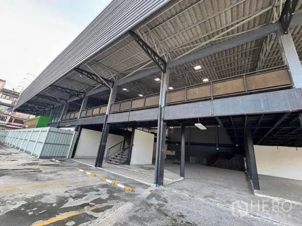 Warehouse for rent in Phra Khanong, Bangkok - Steel-frame warehouse exterior with mezzanine, covered loading bays and marked parking in Phra Khanong.