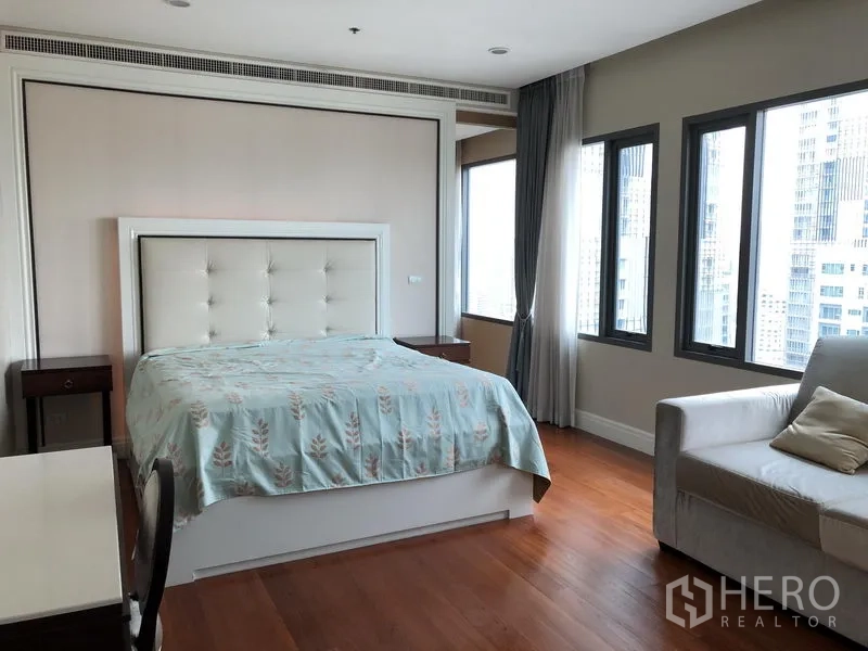 Condominium for rent or sale in Khlong Toei, Bangkok - Master bedroom with upholstered headboard, large windows and city outlook.