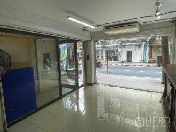 Shophouse for rent in Bang Rak, Bangkok - Bright ground-floor retail space with floor-to-ceiling glass doors opening to the sidewalk and street.