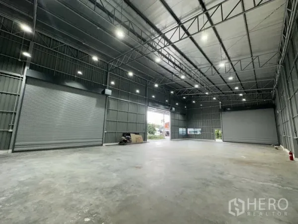 Warehouse for rent in Bang Kapi, Bangkok - Interior showing two automatic roller shutters and a large open loading bay.