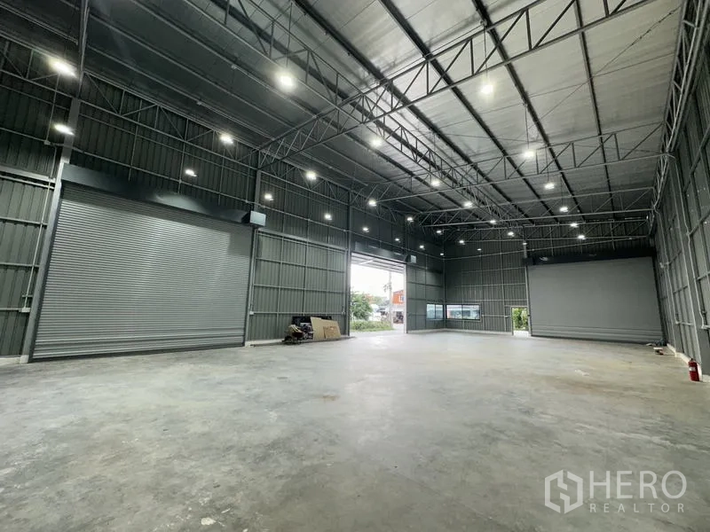 Warehouse for rent in Bang Kapi, Bangkok - Interior showing two automatic roller shutters and a large open loading bay.