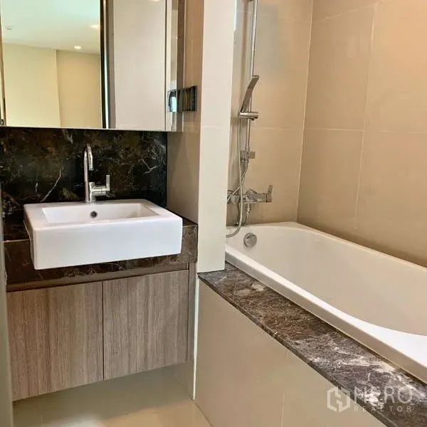 Condominium for rent - Bathroom featuring a square basin, marble counter, and bathtub with handheld shower.