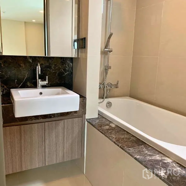 Condominium for rent - Bathroom featuring a square basin, marble counter, and bathtub with handheld shower.