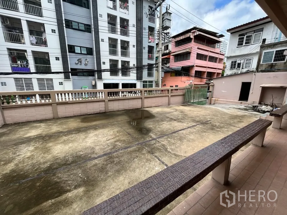 Detached House for rent in Suan Luang, Bangkok - Front patio and parking area bordered by low wall and city buildings.