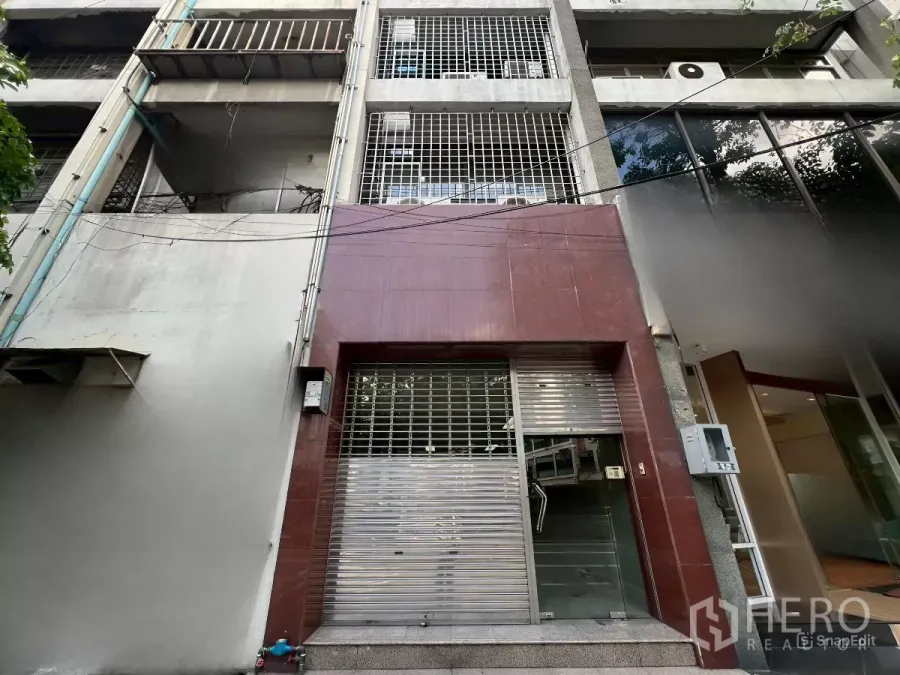 Shophouse for rent in Bang Rak, Bangkok - Street-level view of a five-storey Silom shophouse façade with metal security shutter and grille.