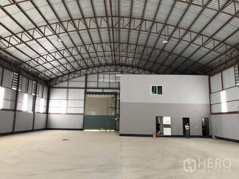 Factory for rent or sale in Bang Len, Nakhon Pathom - Warehouse hall showing tall roller shutter and internal office block on concrete floor.