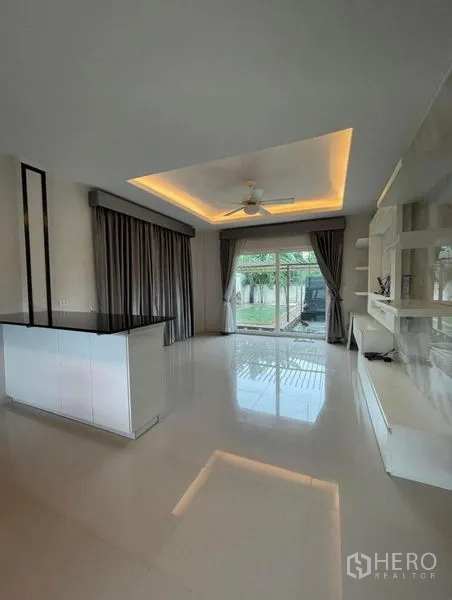 Detached House for sale in Bang Phli, Samut Prakan - Living area opening to the garden via sliding glass doors with tray ceiling and custom TV unit.