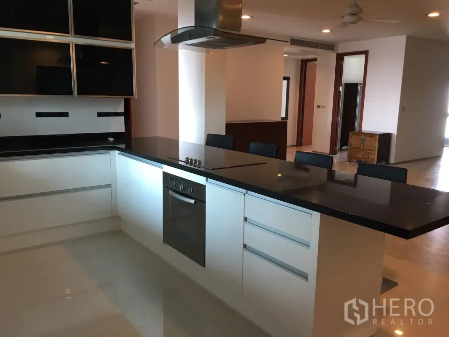 Condominium for rent in Khlong Toei, Bangkok - Open-plan kitchen with black stone island, built-in oven and seating in a Bangkok condo.