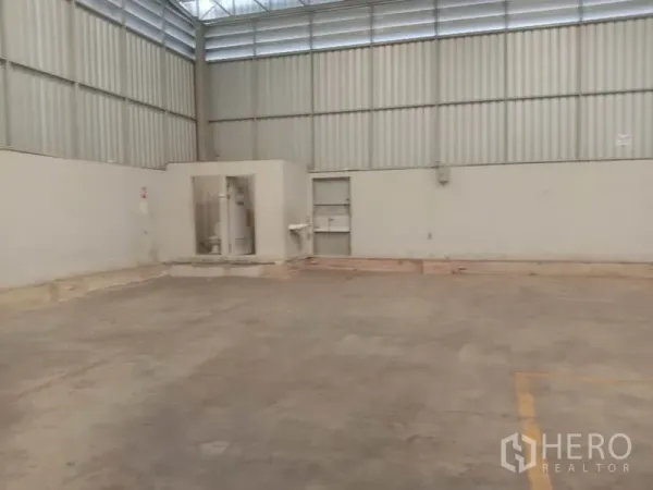 Warehouse for rent in Lat Krabang, Bangkok - Corner of warehouse showing built-in restrooms and sink against concrete flooring.