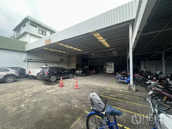 Warehouse for rent in Yan Nawa, Bangkok - Covered loading area with cars and rows of parked motorbikes beside the warehouse.