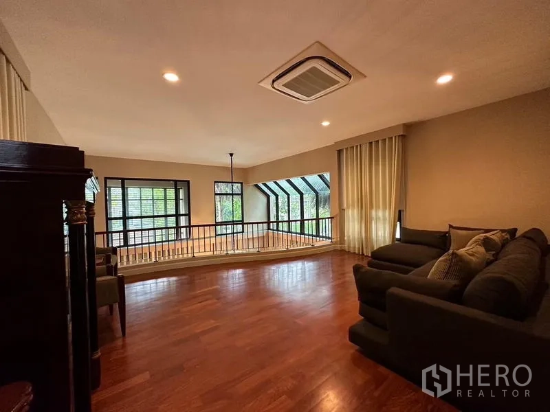 Detached House for rent or sale in Khan Na Yao, Bangkok - Upstairs family lounge with wood floors, bay windows and staircase balustrade.