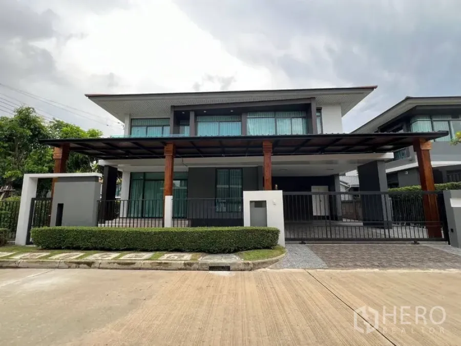 Detached House for rent in Bang Kapi, Bangkok - Front elevation of contemporary house with fence, hedges and pergola roof.