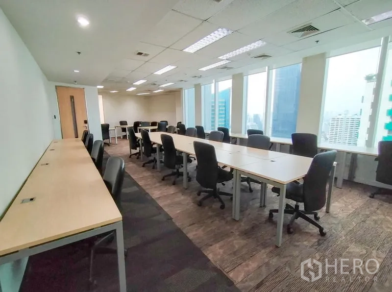 Office Space for rent in Khlong Toei, Bangkok - Spacious office floor with long desks, task chairs and city views from wide windows.