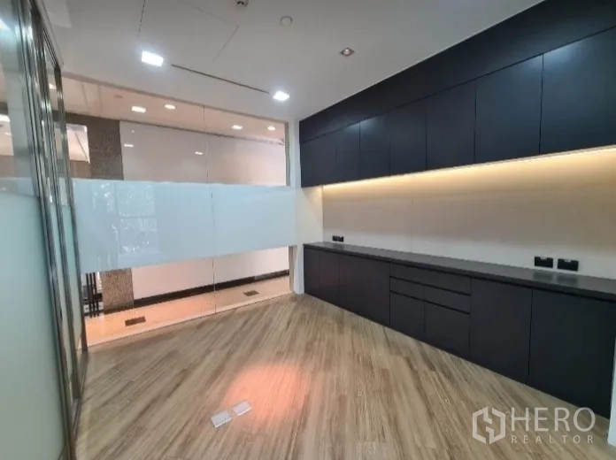 Office Space for rent - Work area with long black cabinetry, under-cabinet lighting, and wood flooring.