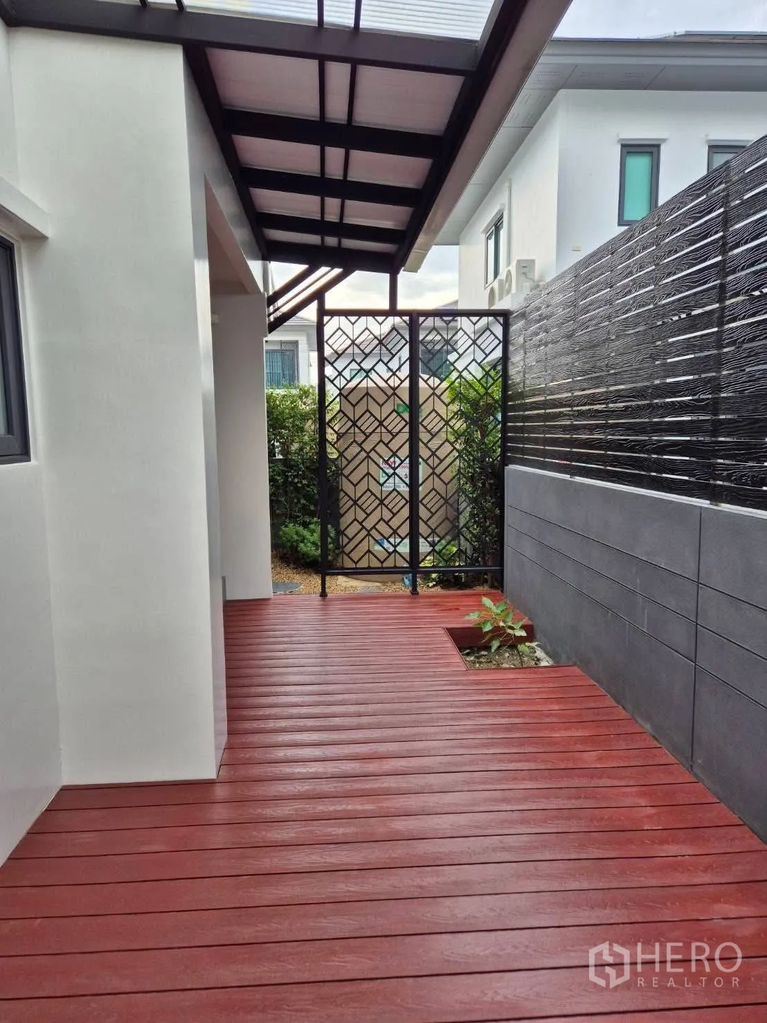 Detached House for sale in Bang Kruai, Nonthaburi - Covered side deck with red wooden flooring and decorative metal gate.