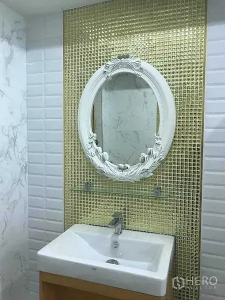 Warehouse for rent in Bang Pakong, Chachoengsao - Bathroom vanity with white basin and ornate oval mirror set against gold mosaic tiles.
