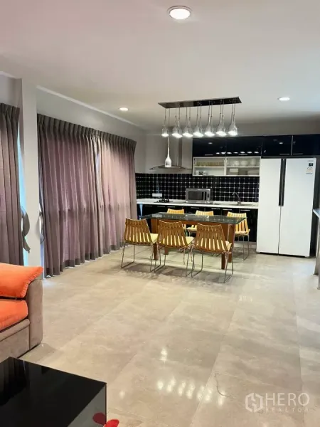 Home Office for rent in Khlong Toei, Bangkok - Open-plan living and dining area with fitted kitchen, pendant lights and full-height curtains.