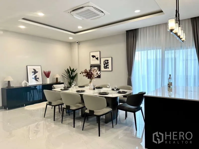 Detached House for rent in Bang Phli, Samut Prakan - Dining area with eight-seat table, pendant lighting and sheer drapes.
