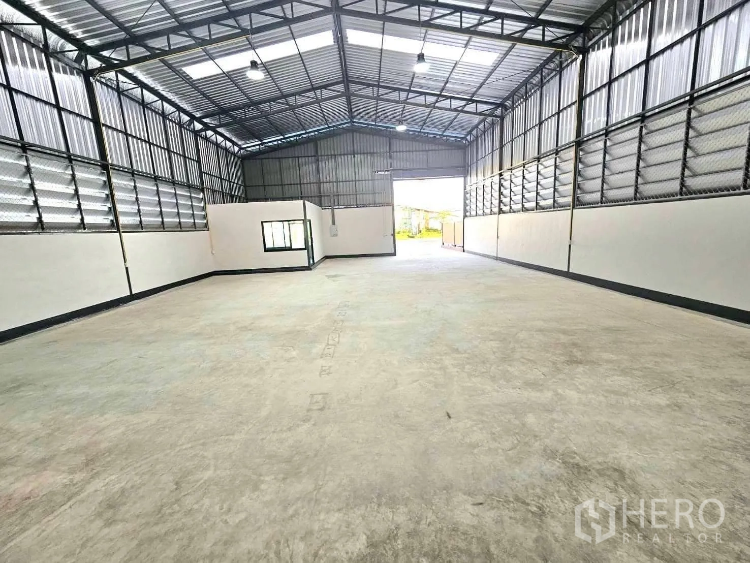 Warehouse for rent in Lam Luk Ka, Pathum Thani - Open-span warehouse interior with a high steel roof, skylights and ventilated side louvres.