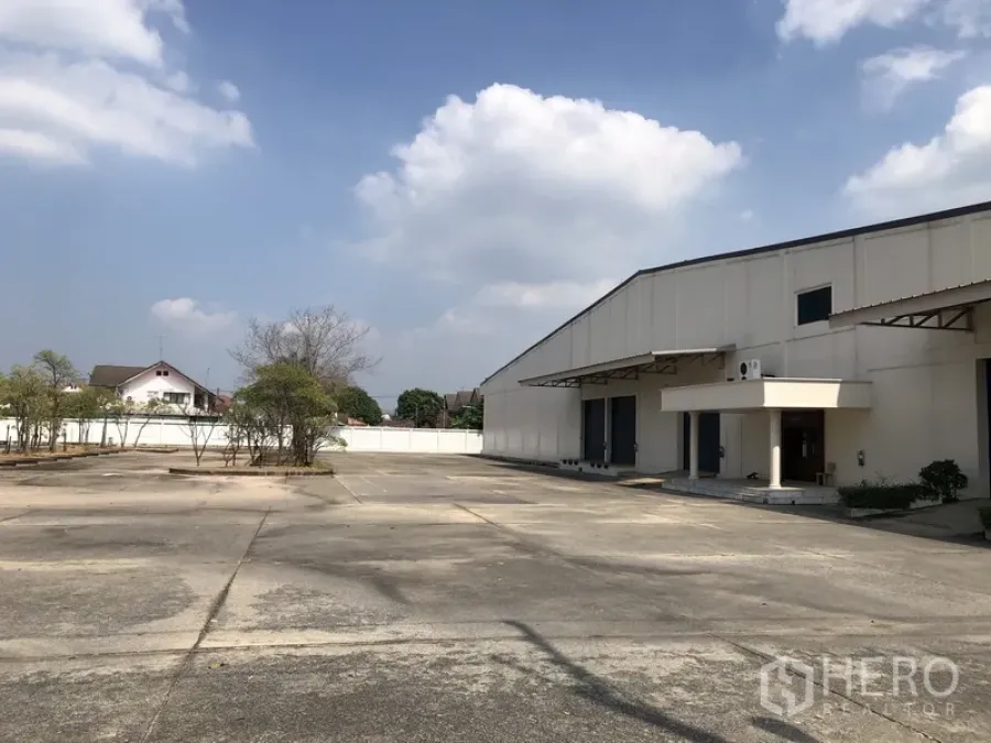 Warehouse for rent in Lam Luk Ka, Pathum Thani - Spacious concrete yard with white warehouse exterior and loading docks in Lam Luk Ka, Pathum Thani