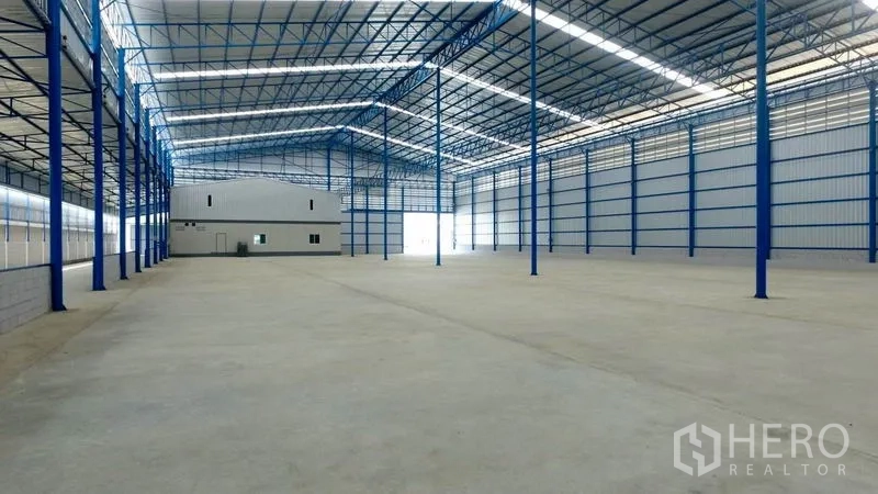 Factory for rent in Mueang Samut Sakhon, Samut Sakhon - Large warehouse interior showing office block at far end and wide loading access.
