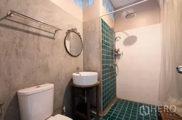 Detached House for rent in Khlong Toei, Bangkok - Bathroom with walk-in rain shower, green tiles, round mirror, vanity, and toilet.