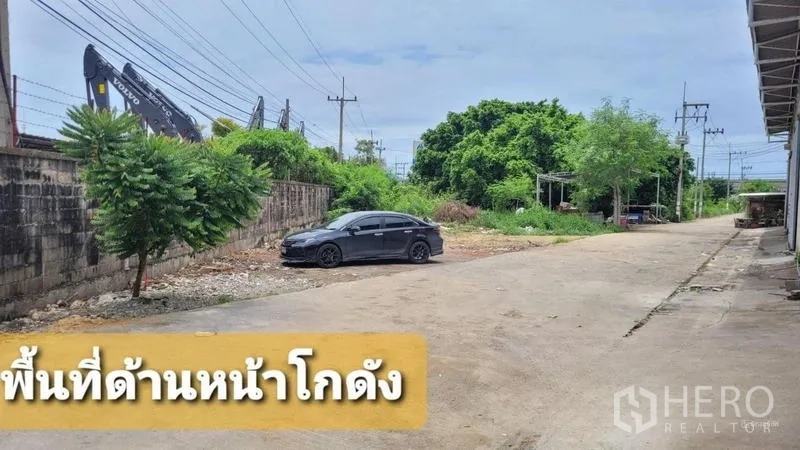 Warehouse for rent in Mueang Samut Sakhon, Samut Sakhon - Front yard and driveway in front of the warehouse with car parking and greenery.
