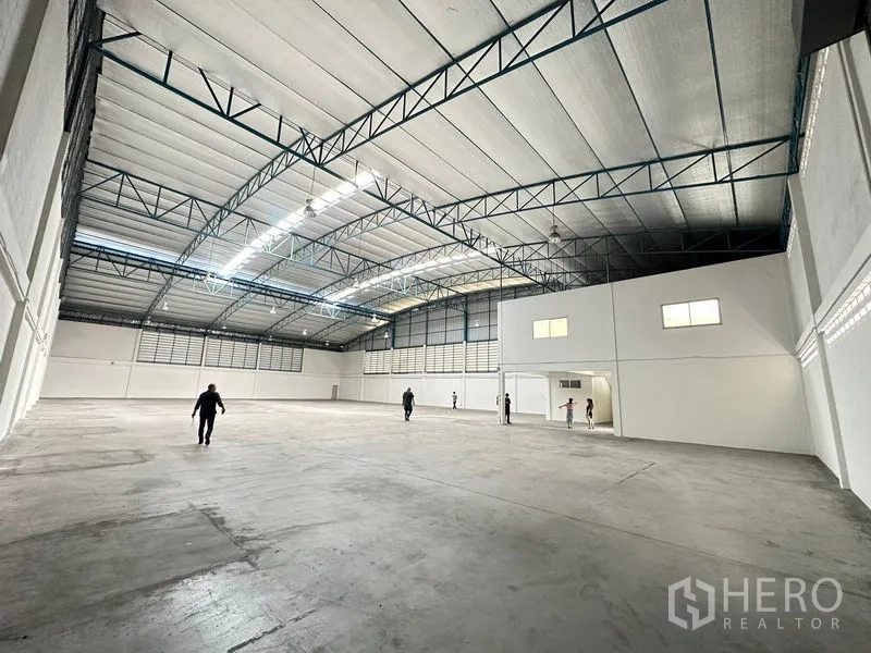 Factory for rent in Si Racha, Chon Buri - Vast clear-span warehouse with multiple skylights and steel trusses over a smooth concrete floor.
