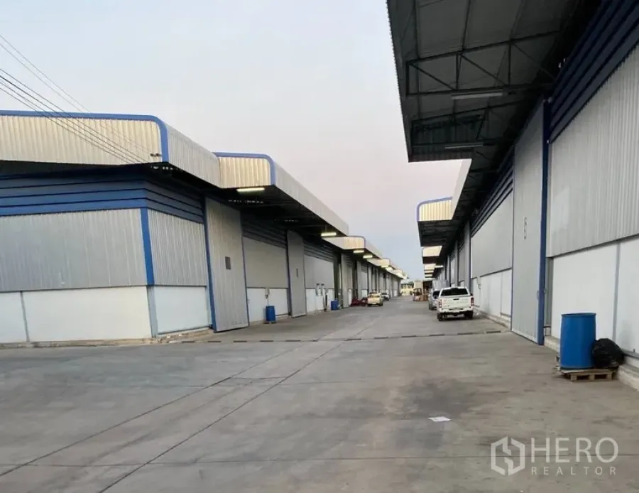 Warehouse for rent in Lat Krabang, Bangkok - Row of modern warehouses with covered loading bays and a wide truck-access road in a Lat Krabang industrial estate.