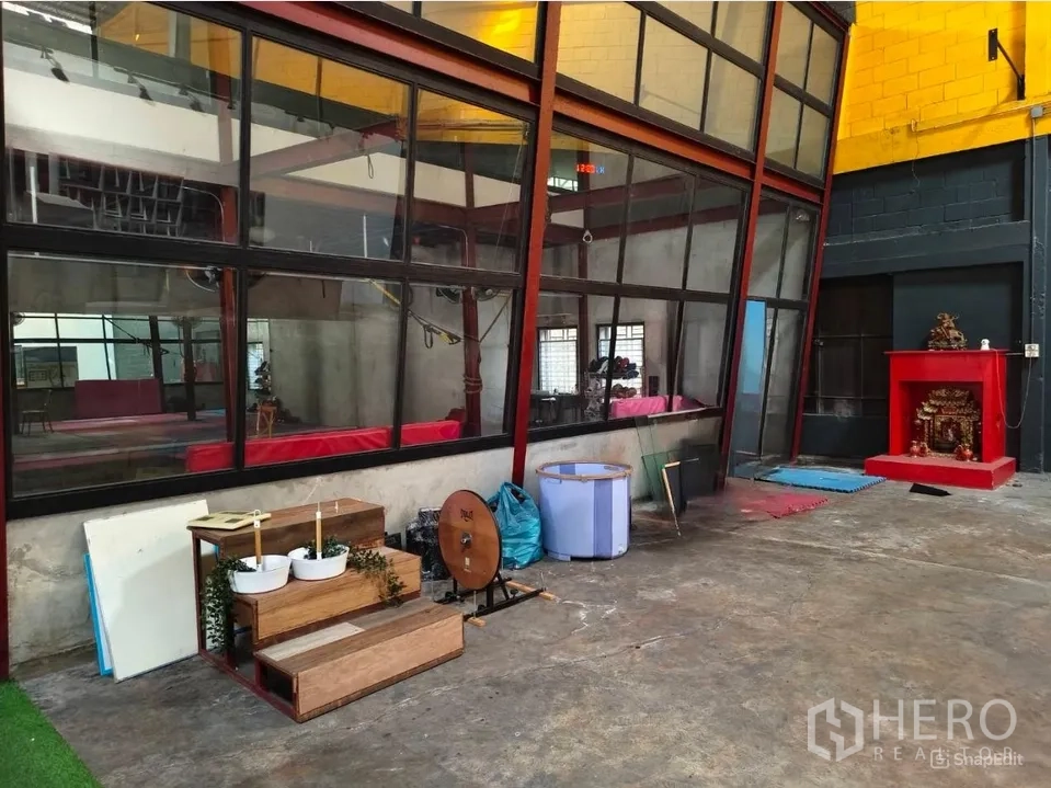 Warehouse for rent in Khlong Toei, Bangkok - Slanted glass wall partition beside open concrete floor and utility area.