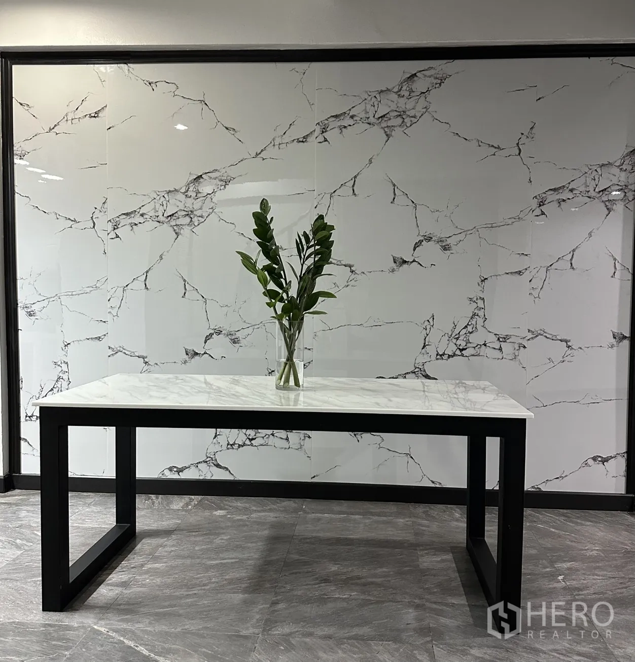 Home Office for rent in Khlong Toei, Bangkok - Marble-top table with a vase of green leaves against a marble-look wall.
