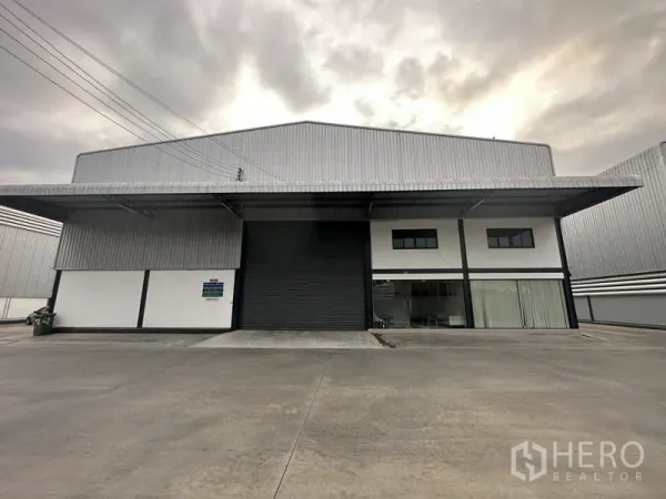 Warehouse for rent in Bang Phli, Samut Prakan - Straight-on facade of the warehouse showing covered loading canopies and a central roller door.