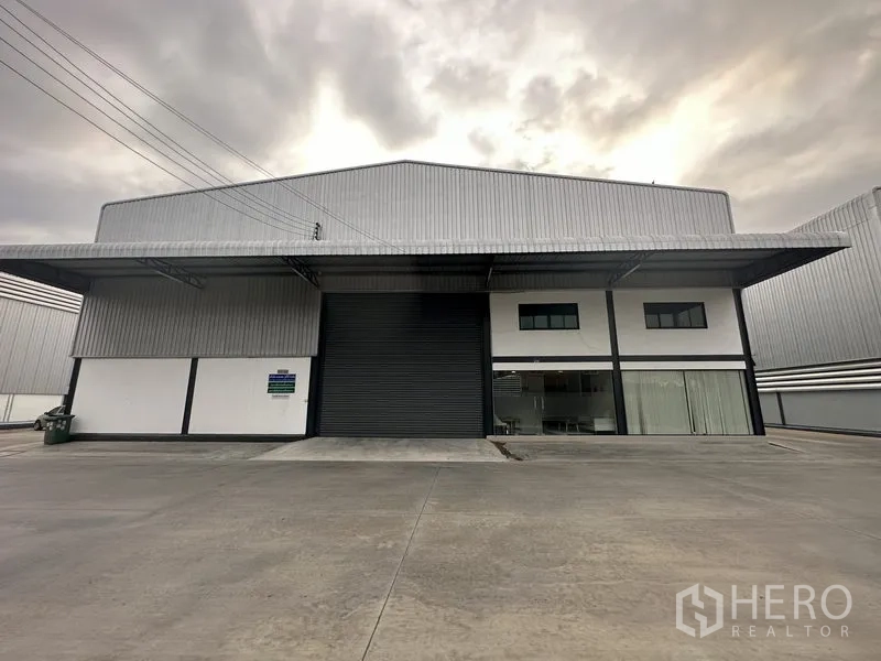 Warehouse for rent in Bang Phli, Samut Prakan - Straight-on facade of the warehouse showing covered loading canopies and a central roller door.